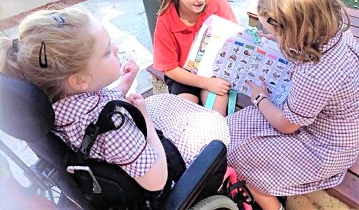 child using PODD communication book with friends